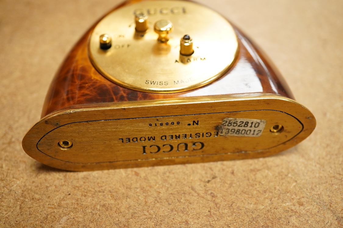 A Gucci gilt and enamelled stirrup shaped alarm clock with plaited and tasselled leather decoration, 9cm high